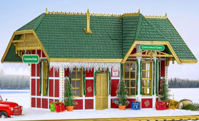 Christmas-themed train station with a red truck and decorated trees on a snowy background