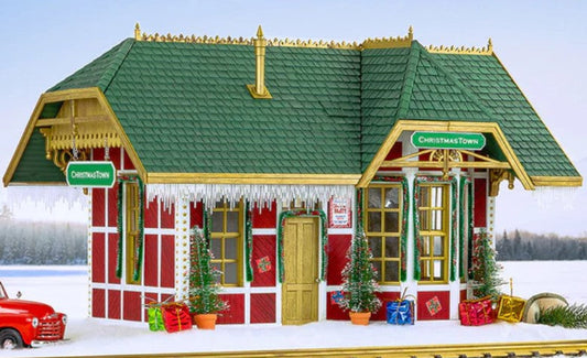Christmas-themed train station with a red truck and decorated trees on a snowy background